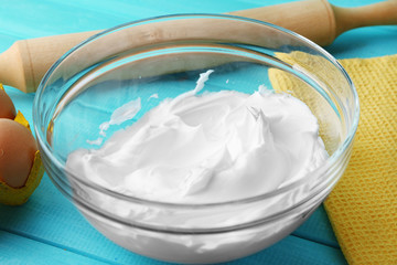 Whipped egg whites for cream on color wooden table, closeup