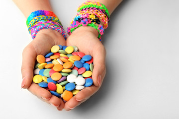 Female hands with bracelets and pile of colorful candies isolated on white