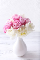 Bouquet of fresh roses and tulips on wallpaper background