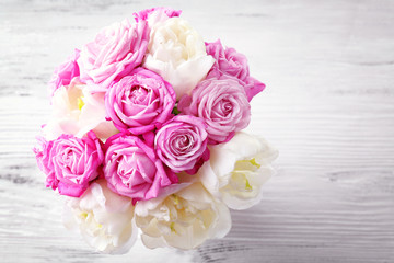 Bouquet of fresh roses and tulips on wooden background