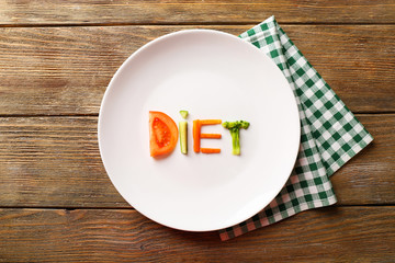 Word DIET made of sliced vegetables in white plate with napkin
