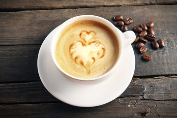 Cup of coffee latte art with grains on wooden background