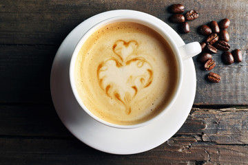 Cup of coffee latte art with grains on wooden background