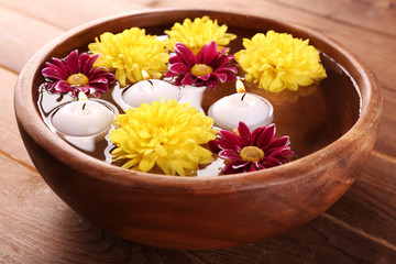 Bowl of spa water with flowers and candles