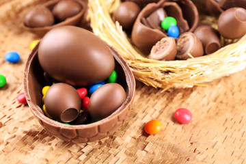Chocolate Easter eggs on wicker fabric in nest, closeup