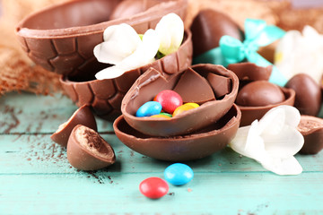 Chocolate Easter eggs with flowers on wooden table, closeup