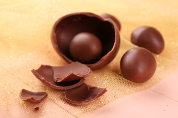 Chocolate Easter eggs on wooden table with tulle, closeup