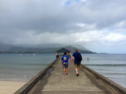 Father and son walk along Hanalei Pier in Kauai