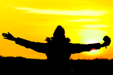 lady silhouette embracing sunset - background yellow