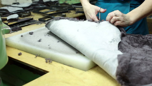 Worker cuts curried animal skins with scissors