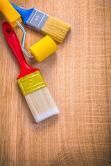 two paint brushes and roller on wooden board