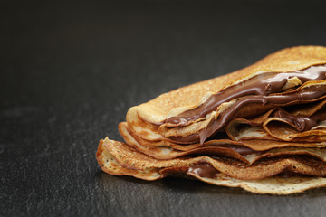 thin crepes or blinis with chocolate cream on slate - obrazy, fototapety, plakaty