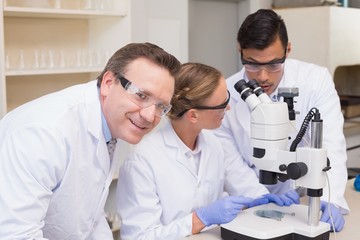 Concentrated scientists working together with microscope