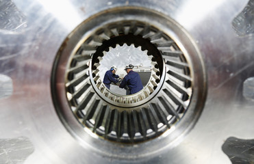 engineers working, seen through a giant cogwheel
