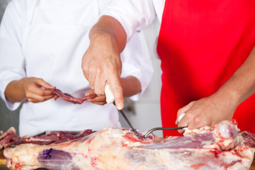 Butcher Cutting Meat By Colleague At Counter