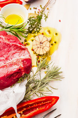 Raw meat with herbs,spices and oil on white wooden background