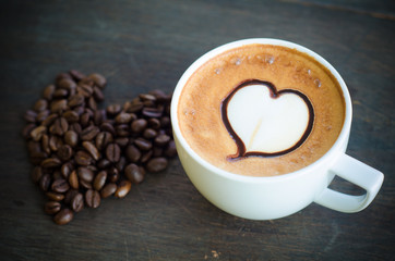 cup of coffee with latte art and heart coffee beans