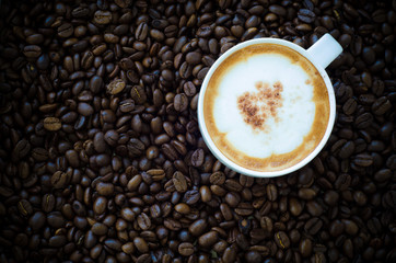 Closeup of a beautiful cup of hot coffee on coffee bean backgrou