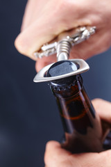 A hand opening a bottle of beer