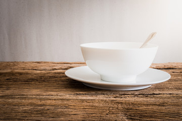 silver spoon in white bowl and white plate on wooden tabletop