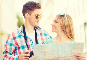 smiling couple with map and photo camera in city