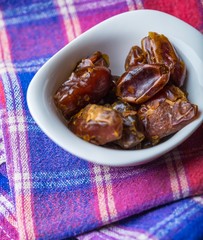 Dried dates in bowl on wooden table..