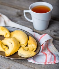 homemade croissants and cup of tea on wooden table..