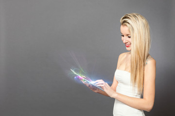 Blonde caucasian woman standing with tablet over grey background