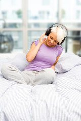 Obraz premium Blonde smiling woman is listening to music with headphones in th