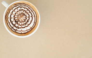 a cup of latte art on brown paper background