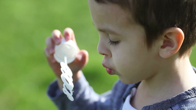 Cute little boy, playing with soap bubbles in the park