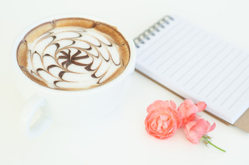 a cup of latte art and rose on white background