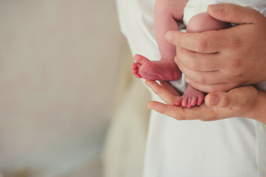 Newborn Baby Feet On Father And Mother Hands, Close-up