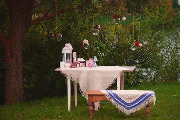 Table and bench in nature with decorations and glass jars with f