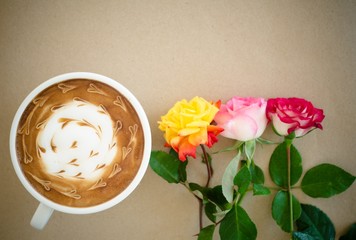 A cup of coffee with latte art and rose on brown paper backgroun