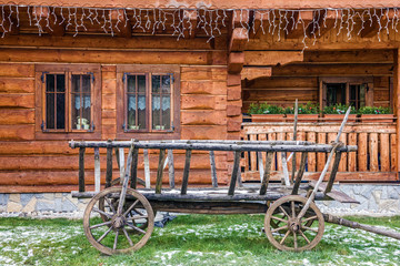 Fototapeta premium Vintage old rough wooden cart and rural house
