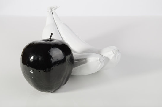 Black Apple And Two White Bananas.