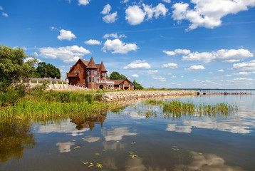 Fototapeta na wymiar Modern house on the lake in summer sunny day in Novgorod region,