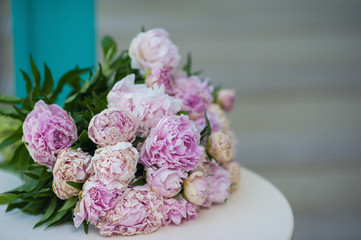 Pink and white bouquet of peonies lies on a white table