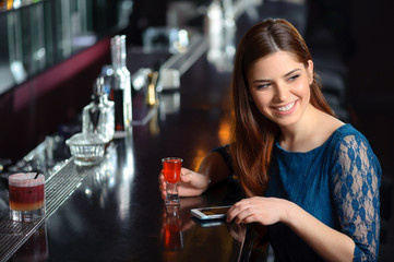 Young woman uses her phone in the bar
