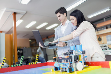 Two smart students programming a robot