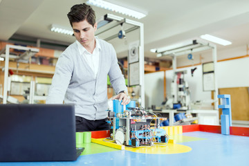 Electrical engineer programming a robot during robotics class