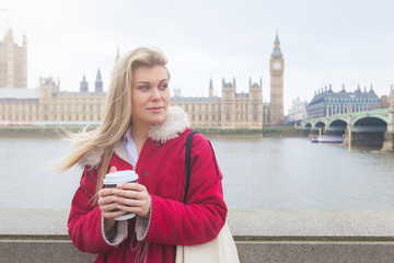 Beautiful blonde young woman holding cup of tea in London