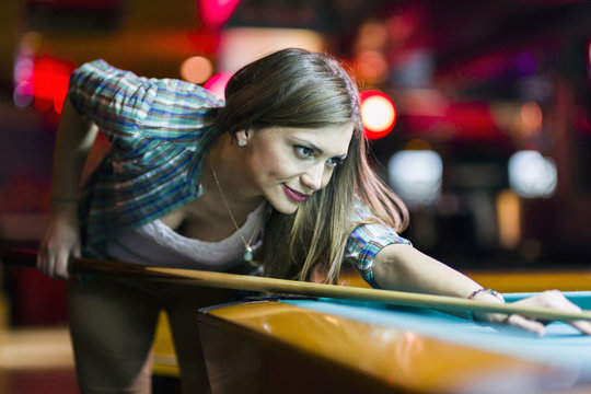 Young beautiful young lady aiming to take the snooker shot