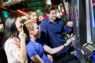 Friends gambling in a casino playing slot and various machines