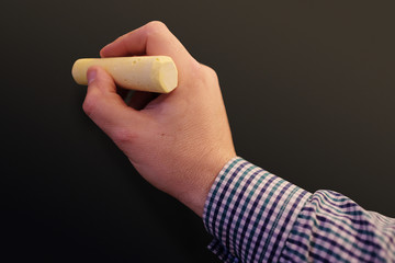 Close up of male hand writing on a blackboard