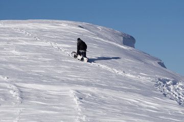 Snowboarder climbing a snowy mountain