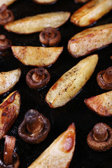 Baked potatoes with mushrooms and spices on pan close up
