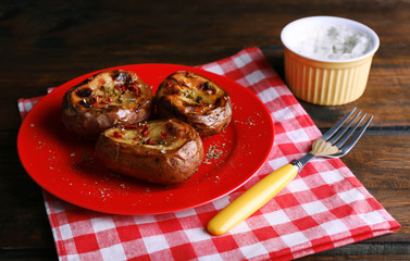 Baked potatoes on plate and sauce on table close up