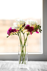 Beautiful spring flowers in glass vase on windowsill background